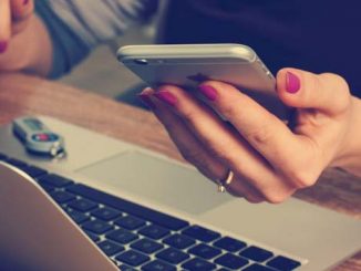 Woman checking her iPhone instead of her Laptop
